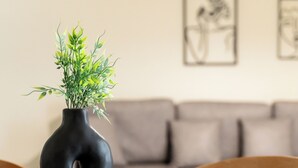 A round table with a black vase containing green plants, surrounded by wooden chairs. - Elysee apartment 2 (Athens)