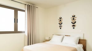 A bedroom with a bed, curtains, a nightstand, and wall decor. - Elysee apartment 2 (Athens)