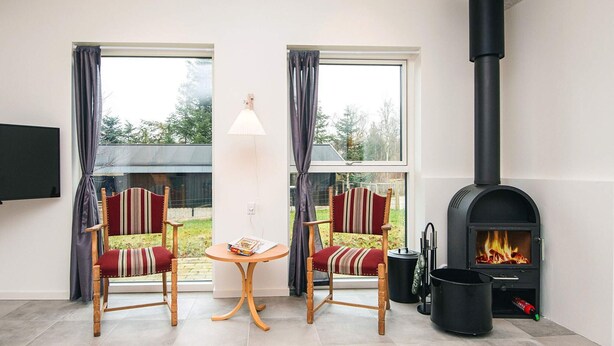 Une pièce confortable avec deux fauteuils, une table, une cheminée et un téléviseur.