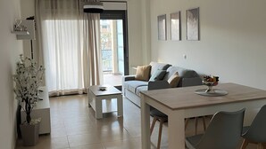 Een moderne woonkamer met een eethoek, een bank, een salontafel en een kroonluchter.