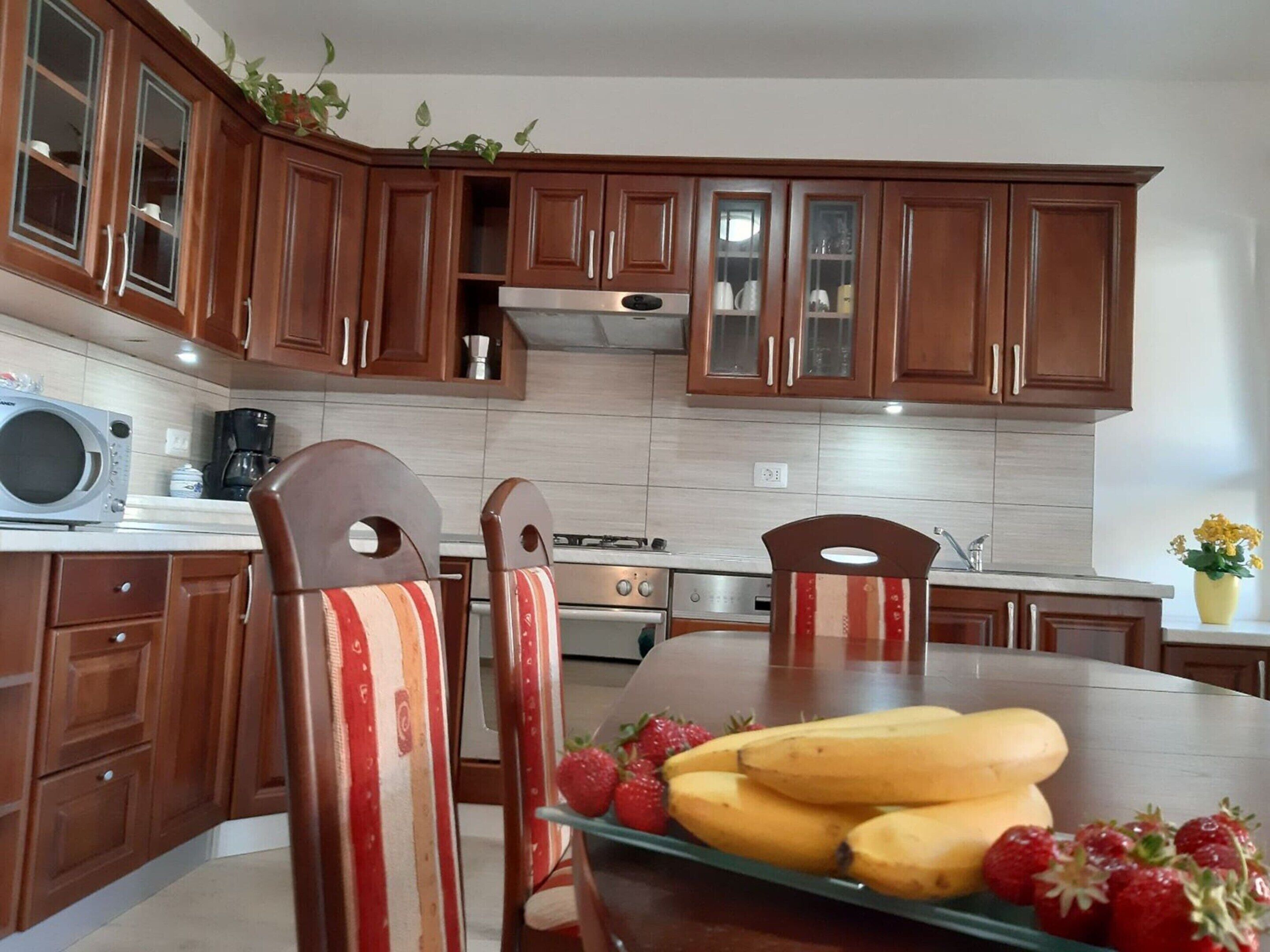 A kitchen with wooden cabinets, a microwave, a coffee maker, and a dining table with chairs.