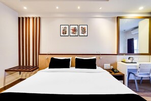 A hotel room with a bed, a desk, a chair, a telephone, and a mirror. - Super Townhouse Oak Kodambakkam (Chennai)
