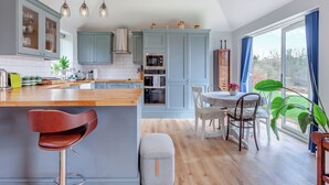 Una cocina moderna con armarios grises, una isla de madera y un comedor con mesa y sillas.