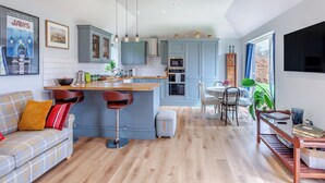 Una cocina moderna con una isla central, taburetes de bar y un comedor con mesa y sillas.