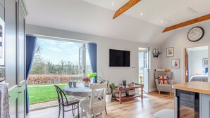 Amplia sala de estar con mesa de comedor, sillas, televisor y vistas al exterior.