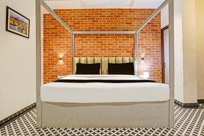 A bed with a metal frame, a brick wall, and patterned floor tiles.