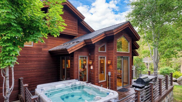 A wooden cabin with a hot tub and deck.