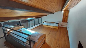 A loft-style bedroom with two bunk beds, a wooden ceiling, and a large window. - Quiet 3-star gite for 6 to 8 people with view, 5min from St Guilhem le désert (Arboras)