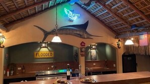 A bar area with a 'FLOODED' sign, a neon sign, and a large fish mural on the wall. - Brand new Loft in Loreto! Short walk to the beach, marina, and downtown! (Loreto)