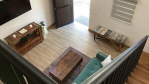 A spacious living area with a wooden coffee table, a green sofa, a wooden bench, and a TV mounted on the wall. - Brand new Loft in Loreto! Short walk to the beach, marina, and downtown! (Loreto)