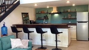 A modern kitchen with a central island, bar stools, and a refrigerator. - Brand new Loft in Loreto! Short walk to the beach, marina, and downtown! (Loreto)