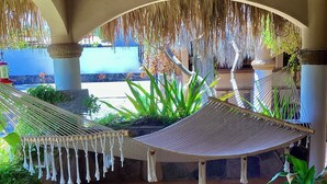 A covered outdoor area with a thatched roof, a hammock, and potted plants. - Brand new Loft in Loreto! Short walk to the beach, marina, and downtown! (Loreto)