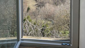 A room with a large window offering a view of a mountainous landscape. - Home for nature lovers, 5 minutes from the village (Valleto)