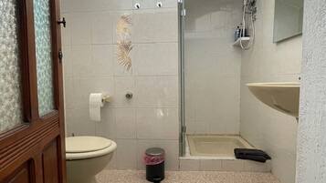 A bathroom with a toilet, shower, and sink.