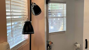 A bathroom with a hairdryer, a black lamp, and a toilet paper holder.