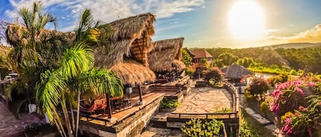A tropical resort with thatched-roof structures, a stone pathway, and lush greenery.