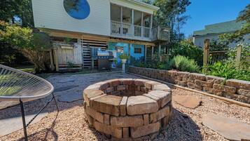 A house with a circular fire pit, a covered outdoor seating area, and a large window overlooking the yard.