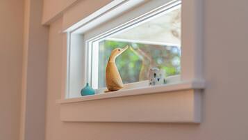 Eine Fensterbank mit einer hölzernen Entenfigur und einer kleinen Vase.
