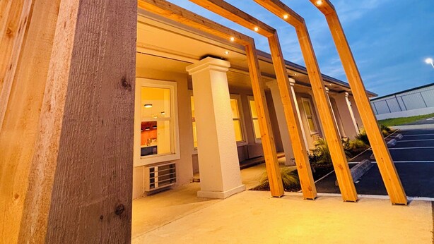 A building with a modern architectural design, featuring a series of wooden beams and columns. - The Depot Hotel (Taylor)