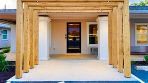 A wooden pergola entrance to a building with a door and windows. - The Depot Hotel (Taylor)