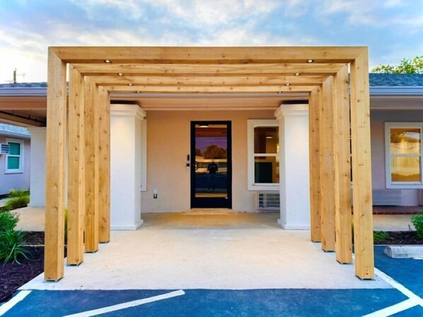 A wooden pergola entrance to a building with a door and windows. - The Depot Hotel (Taylor)