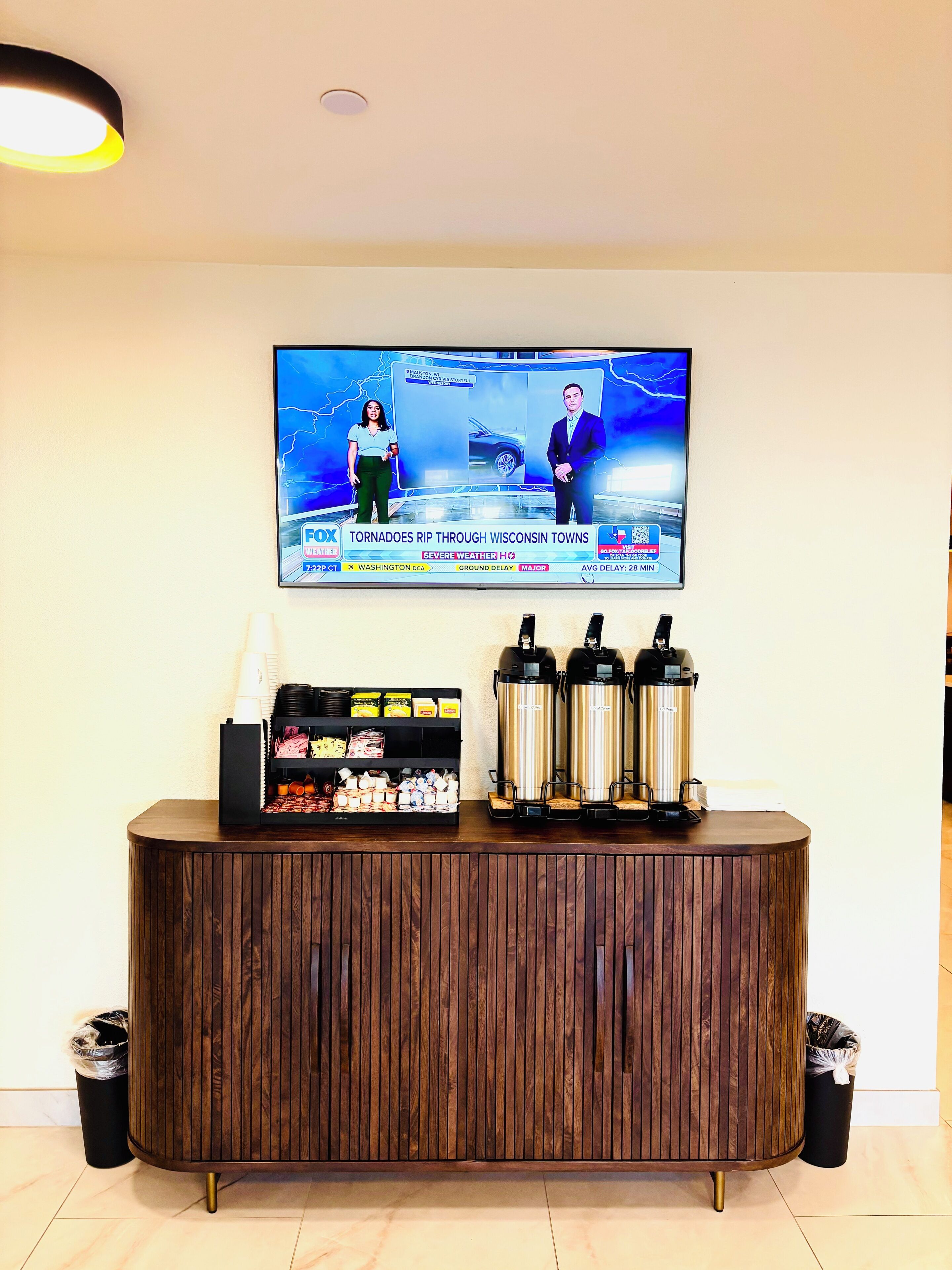 Un espace d’accueil équipé d’un téléviseur diffusant les prévisions météorologiques, d’un coin café et d’un meuble en bois.