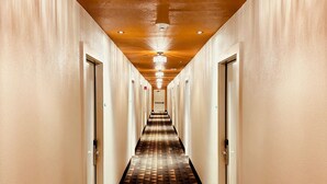 A hotel hallway with a geometric patterned floor, a chandelier, and doors on both sides. - The Depot Hotel (Taylor)