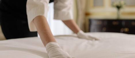 A person in a white uniform and gloves adjusting a bed.