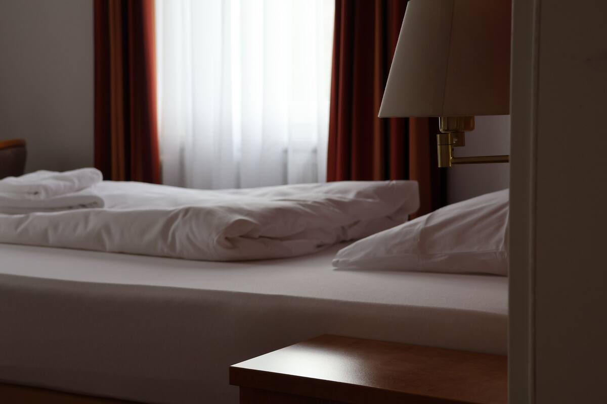 Een hotelkamer met een bed, nachtkastje en lamp.
