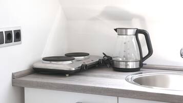 Una kitchenette con estufa, hervidor y lavamanos.