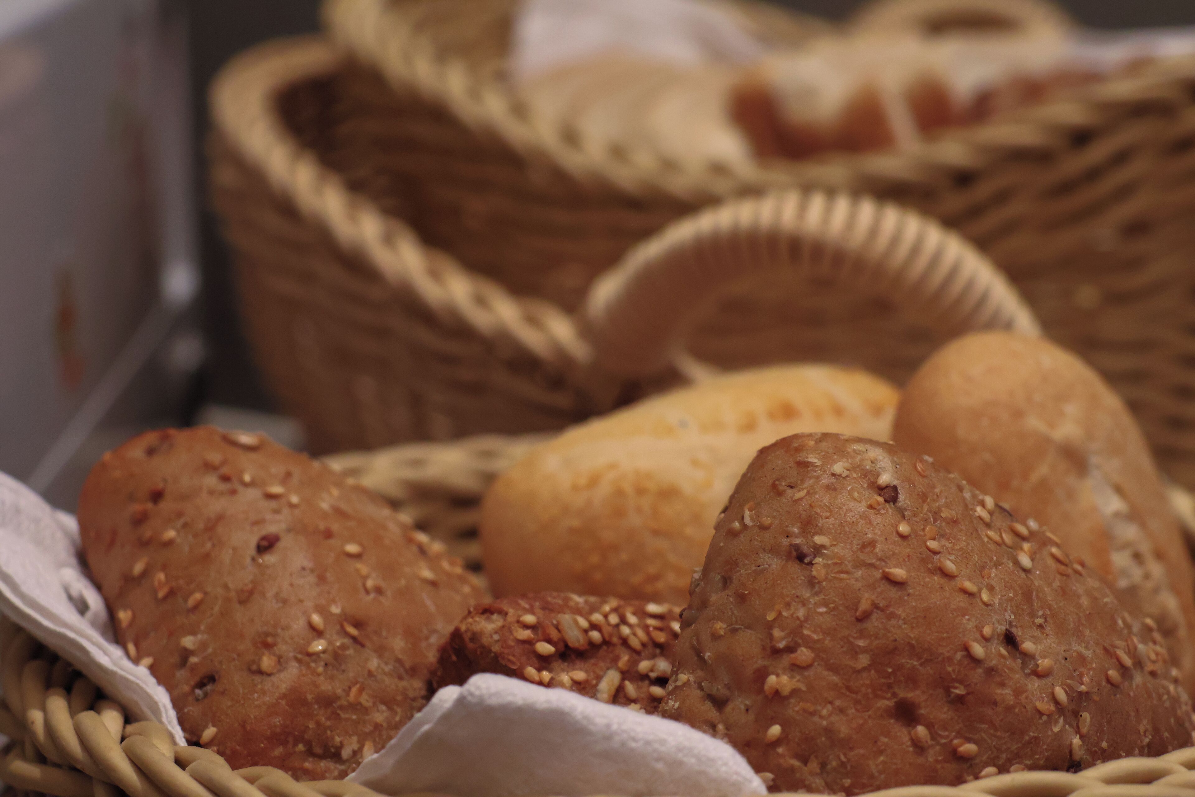 A basket of various breads, including whole grain and seeded varieties.