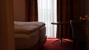 Una habitación de hotel con una cama, una mesita redonda pequeña y una silla.