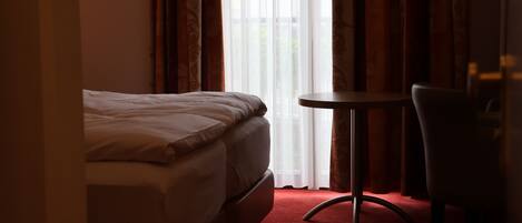 A hotel room with a bed, a small round table, and a chair.
