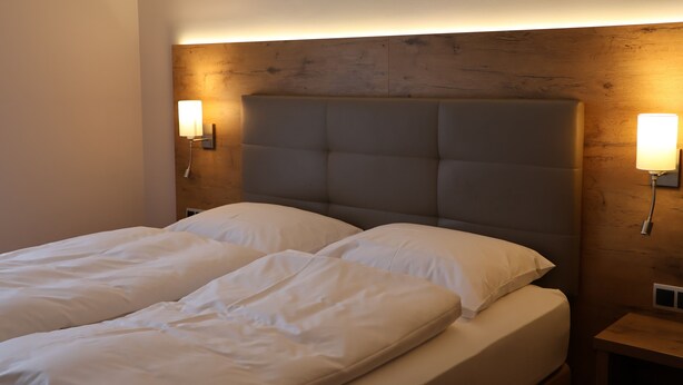 A double bed with a wooden headboard, two bedside lamps, and a nightstand. - Hotel an der Therme (Bad Durkheim)
