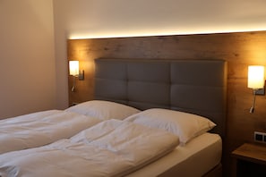 A double bed with a wooden headboard, two bedside lamps, and a nightstand. - Hotel an der Therme (Bad Durkheim)