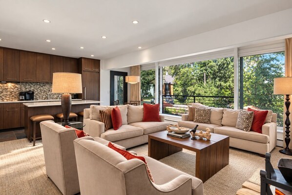 A modern living room with a sofa set, a coffee table, and a kitchen area with a bar.