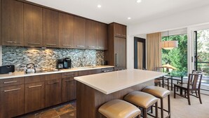 Une cuisine moderne avec des meubles de couleur bois foncé, un pare-feu en carreaux et un grand îlot central doté de tabourets de bar.