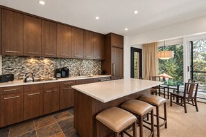 A modern kitchen with dark wood cabinets, a tiled backsplash, and a central island with bar stools.