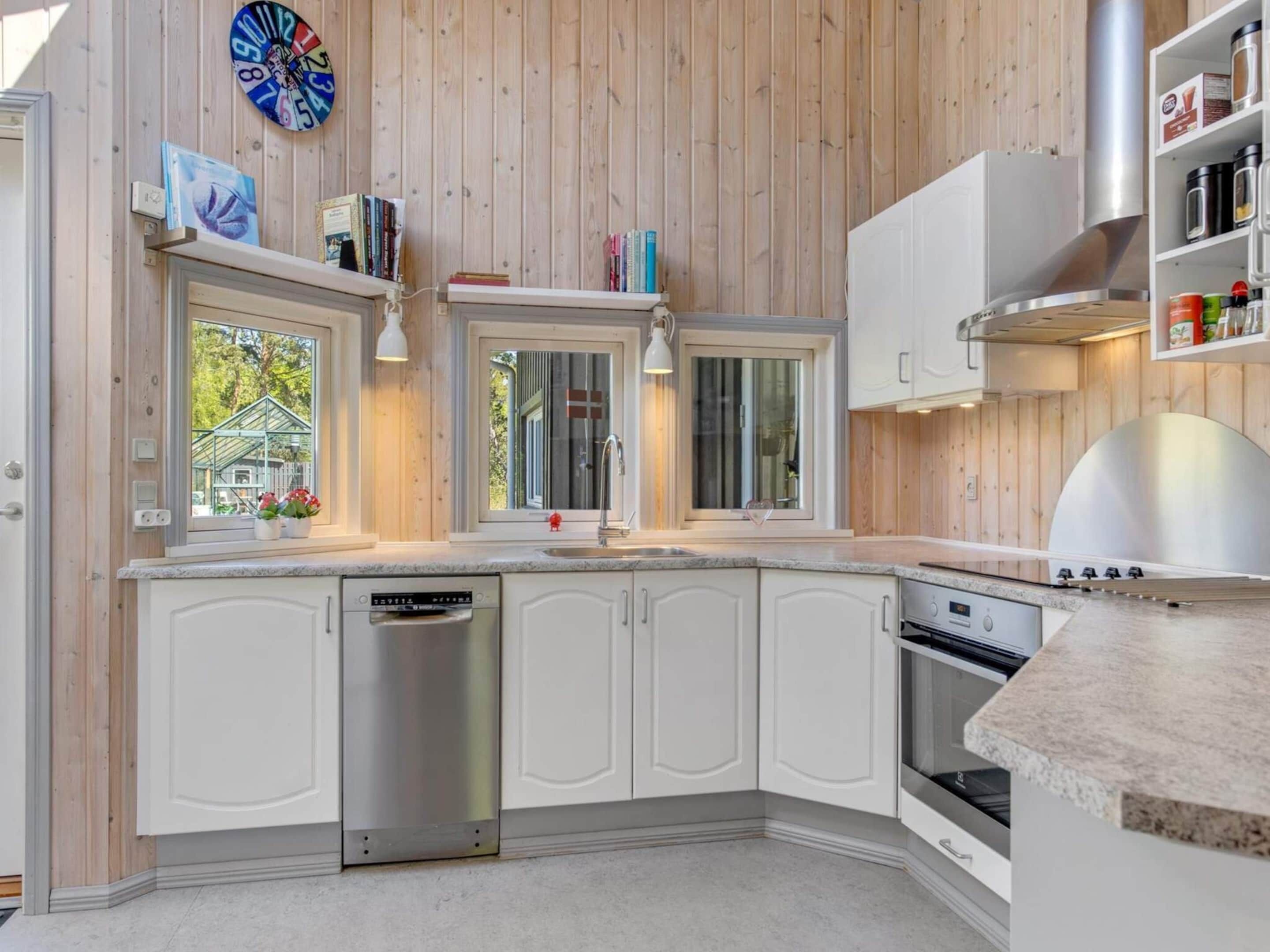 A modern kitchen with white cabinetry, a dishwasher, an oven, and a built-in grill.