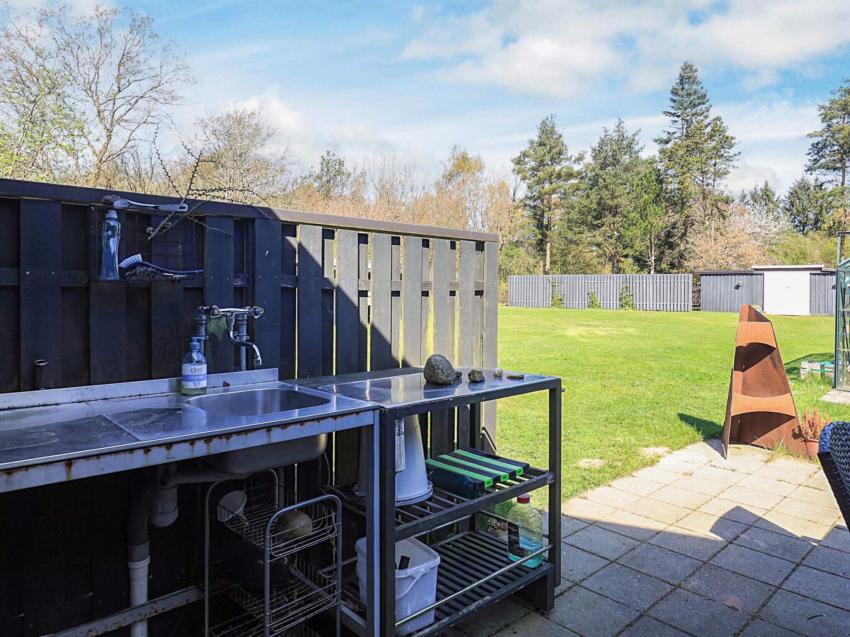 An outdoor kitchen with a sink, faucet, and storage shelves.