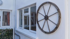 A white building with a window and a large wooden wheel decoration on the wall. - Escape to Barnhayes, a charming retreat in the picturesque village of Hartland. (Hartland)