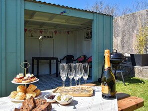 Ein gedeckter Tisch mit Speisen, verschiedenen Gebäcken, einer Flasche Canti-Wein und leeren Weingläsern.