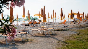 A beach with rows of sun loungers and umbrellas. - Apartment in Valbandon Near Beach & Pool (Fazana)