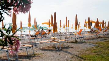 A beach with rows of sun loungers and umbrellas.