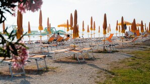 A beach with rows of sun loungers and umbrellas. - Lovely Relaxing Studio With Terrace (Fazana)