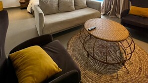 Una moderna camera d'albergo con un letto, due divani, un tavolino rotondo e un'ampia finestra con tende.