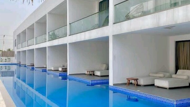 Un hotel moderno con una grande piscina coperta, numerosi balconi e un design pulito e contemporaneo.