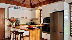 Una cocina moderna con armarios de madera, una isla central con taburetes, un refrigerador y varios electrodomésticos.