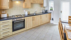 Une cuisine moderne avec des meubles en bois, une cuisinière à gaz, un four et un four à micro-ondes.
