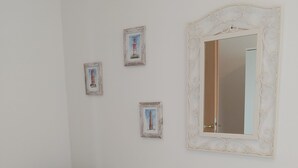 Una habitación con piso de madera, una silla marrón con cojín floral y tres cuadros en la pared.